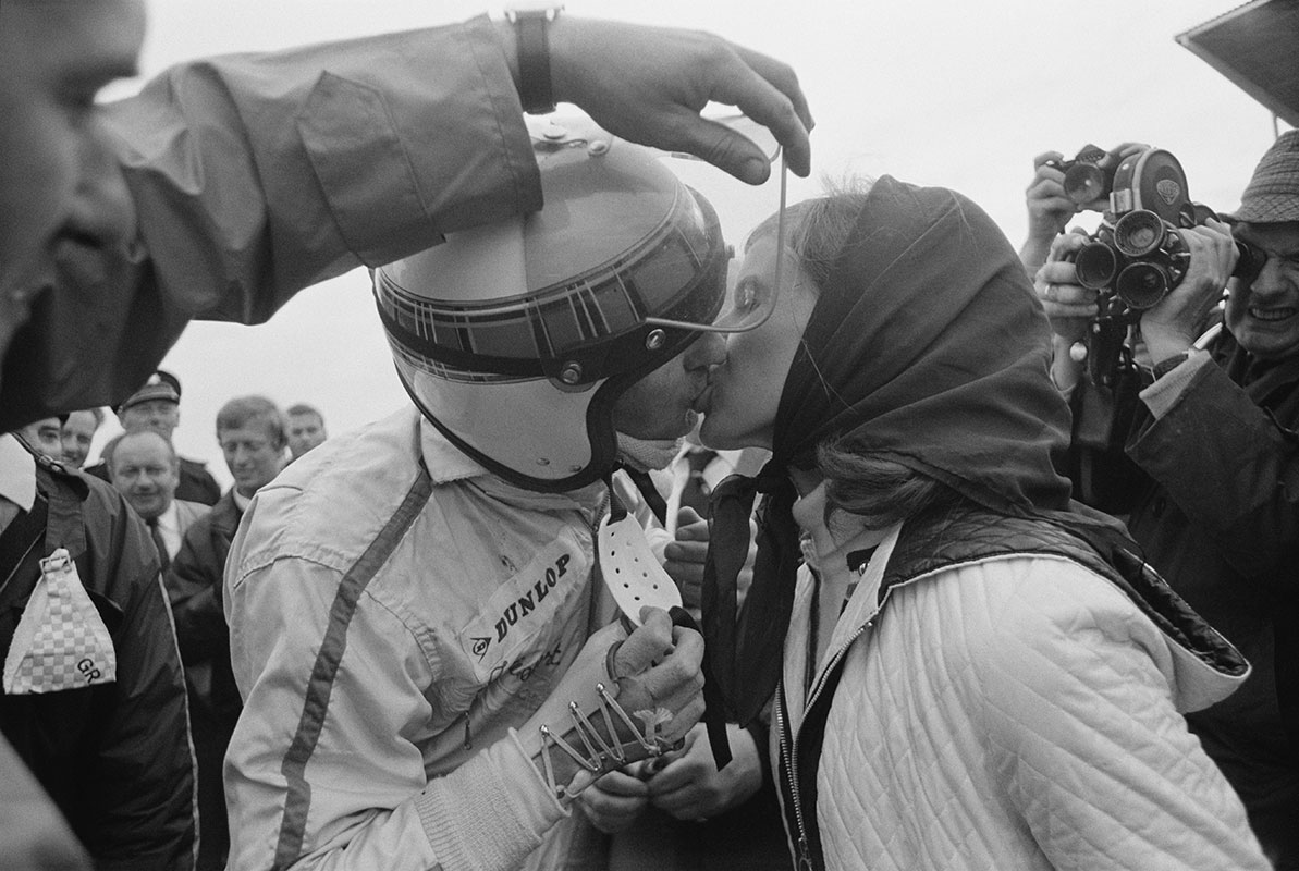 Helen Stewart congratulates her husband Jackie on his 1968 Dutch Grand Prix victory at Zandvoort with a kiss. [Note that someone has to hold up his visor due to his broken right wrist] (Netherlands, 1968)